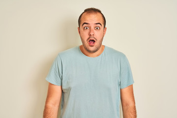 Fototapeta premium Young man wearing blue casual t-shirt standing over isolated white background afraid and shocked with surprise expression, fear and excited face.