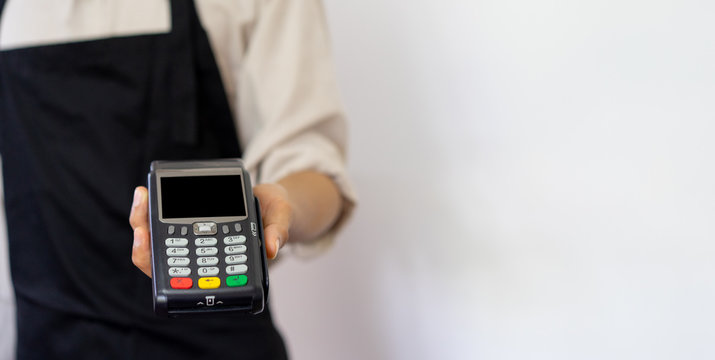 close up business owner man hand showing a electronic banking money machine for receiving purchase from customer in the shop , business and  technology of contactless payment concept