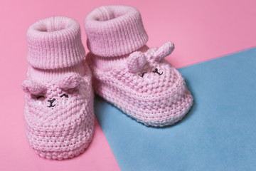 Pink newborn crochet booties on a pastel paper background