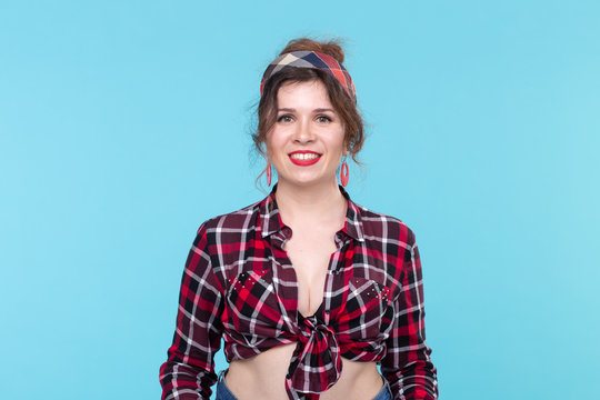 Positive beautiful young woman in a plaid vintage shirt looking at the camera and smiling posing on a blue background.