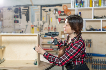 furniture factory, Small-Sized Companies and female worker concept - woman with a drill on the factory.
