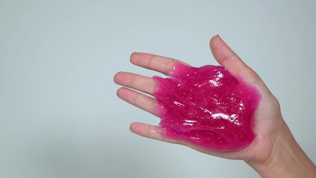 Closeup view of female hands with pink manicure enjoying playing pink sticky slime. Anti stress toy interesting to everybody. Real time full hd video footage.