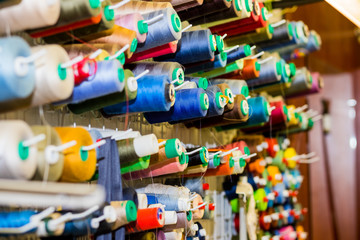 Fototapeta na wymiar variety big and used spools of colorful sewing threads. Tailor shop theme background, Textiles and clothing industry concept. selective focus.Colorful thread spools used in fabric and textile industry