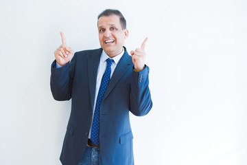 Middle age business man smiling and pointing to the side over white background