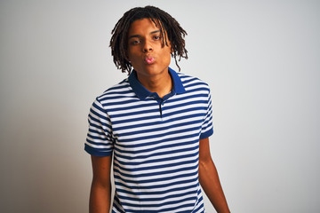 Fototapeta premium Afro man with dreadlocks wearing striped blue polo standing over isolated white background looking at the camera blowing a kiss on air being lovely and sexy. Love expression.