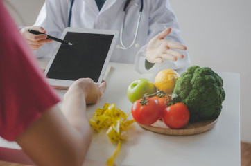 friendly nutritionist female doctor or medical using tablet and talking about diet plan with...