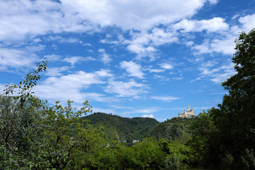 German castle Marksburg on the hill in the rhineland nad trees and blue sky with white clouds - Stockphoto