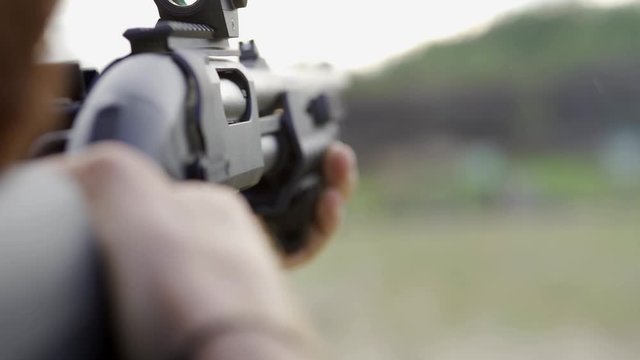 Courageous man with a beard in glasses, shoots from a shotgun in the open air. Close up, slow mo.