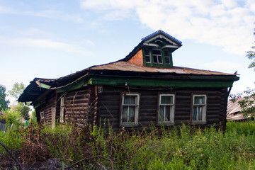 Fototapeta na wymiar old rickety wooden hut pimped in a Russian village in summer under a blue sky
