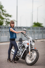 Fototapeta na wymiar Fashion sexy woman is standing near classic style cruiser motorbike. Girl biker with perfect fit slim body on highway. The spirit of freedom and independence. 