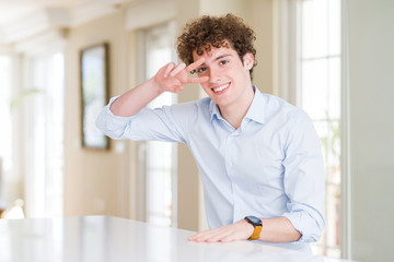 Obraz premium Young business man with curly read head Doing peace symbol with fingers over face, smiling cheerful showing victory