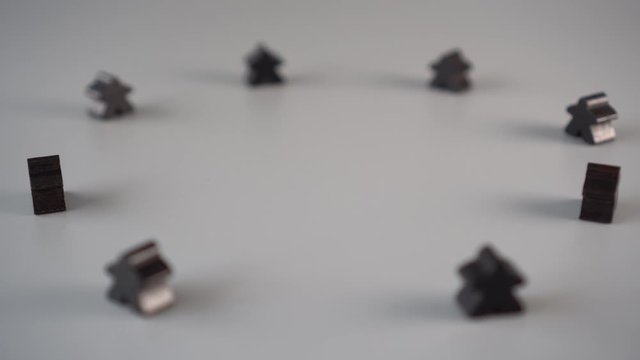 The hand removes the red figure from the environment of black figures on a gray surface. The concept of the dismissal of the leader from the team