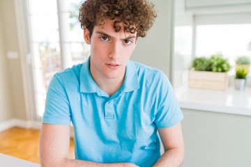 Fototapeta premium Young handsome man wearing casual blue t-shirt at home skeptic and nervous, disapproving expression on face with crossed arms. Negative person.