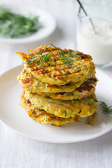 Zucchini, carrot, parmesan fritters on plate with dill and yogurt
