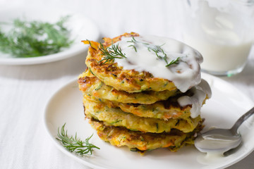 Zucchini, carrot, parmesan fritters on plate with dill and yogurt