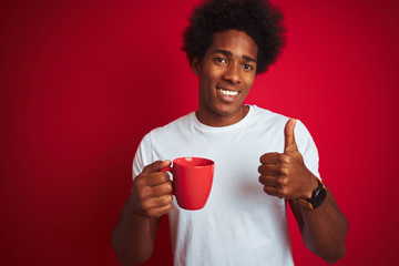Young african american man drinking a cup of coffee standing over isolated red background happy with big smile doing ok sign, thumb up with fingers, excellent sign