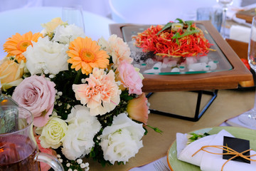 Floral bouquet and salad on a decorated banquet table in luxury restaurant.