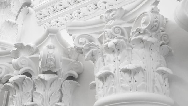 Decorative item made of white plaster on ceiling and wall. Beautiful ornament and relief stucco interior
