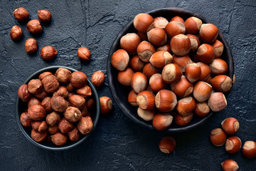 Peeled and unpeeled hazelnuts in a bowl.Top view with copy space.