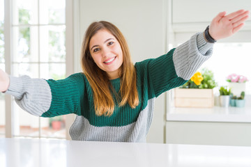 Young beautiful plus size woman wearing casual striped sweater looking at the camera smiling with open arms for hug. Cheerful expression embracing happiness.