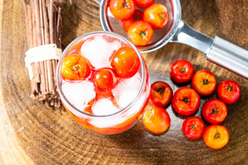 Acerola juice and Acerola fruit in a sieve and wooden background