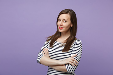Fototapeta premium Beautiful young woman girl in casual striped clothes posing isolated on violet purple background studio portrait. People lifestyle concept. Mock up copy space. Looking camera, holding hands crossed.