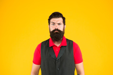 Fototapeta premium Shop staff concept. Salesman cashier career. Hiring shop store worker. Hospitality staff. Restaurant cafe staff wanted. Man bearded hipster with mustache wear vest and shirt uniform yellow background