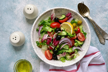 Vegetable salad with tomato, cucumber olives and lettuce. Top view with copy space.