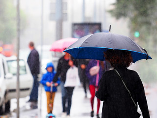 Rain in the city, pedestrians. People walking with umbrellas and  raincoats in the rainy city