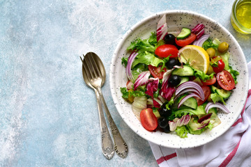 Vegetable salad with tomato, cucumber olives and lettuce. Top view with copy space.