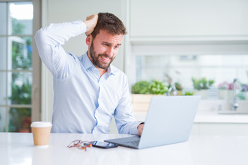 Handsome man working using computer laptop and drinking a cup of coffee stressed with hand on head, shocked with shame and surprise face, angry and frustrated. Fear and upset for mistake.