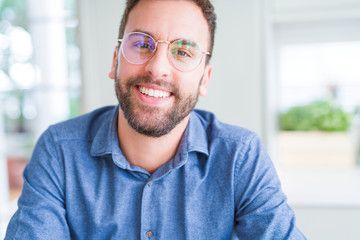 Handsome man wearing glasses and smiling relaxed at camera