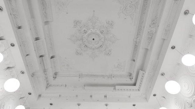 Decorative item made of white plaster on ceiling and wall. Beautiful ornament and relief stucco interior