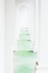 Conceptual view along bright white arched corridor tunnel with green floor.