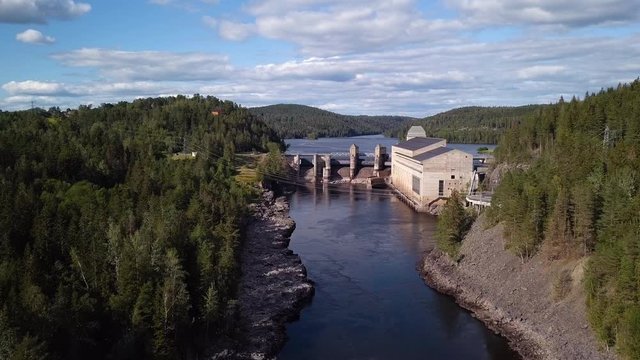 Aerial, drone shot, over at Glomma river, towards the Solbersfossen hydroelectric power station dam, on a sunny day, in Spydeberg, Ostfold, Norway