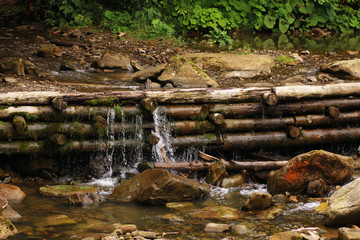Fototapeta na wymiar A small artificial waterfall in a forest of logs