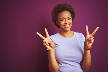 Young beautiful african american woman with afro hair over isolated purple background smiling...