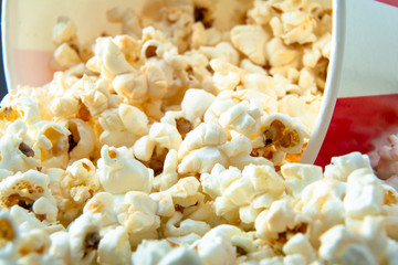 Macro photography of fresh, warm tasty popcorn in a striped paper cup. Close up.