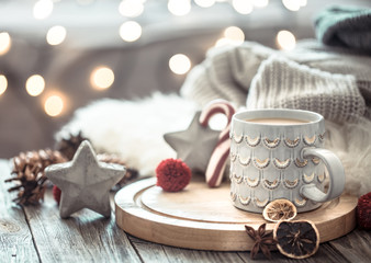 Coffee cup over Christmas lights bokeh in home on wooden table with sweater on a background and...