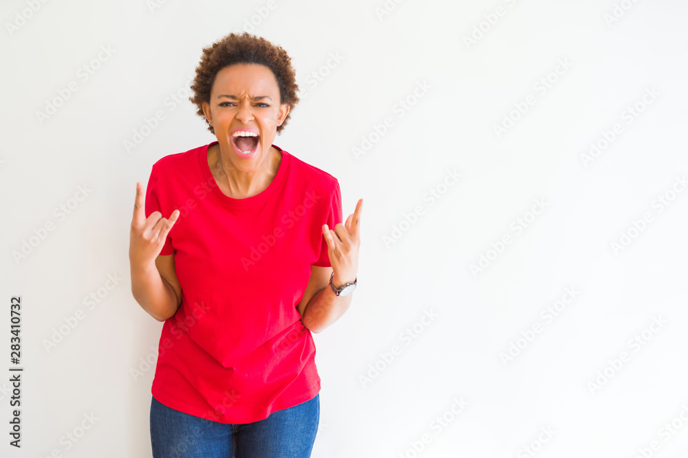 Wall mural young beautiful african american woman over white background shouting with crazy expression doing ro