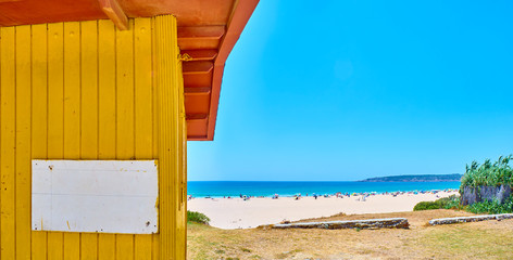 Obraz na płótnie Canvas Playa de Bolonia Beach, a unspoiled white sand beach of Tarifa. And a yellow beach hut with a blank cartel in the foreground. Tarifa, Cadiz. Andalusia, Spain.