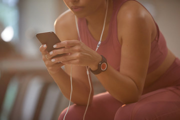 Close up of unrecognizable young woman using smartphone in gym, copy space