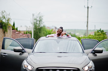 Rich business african woman in silver suv car on sunroof having fun.