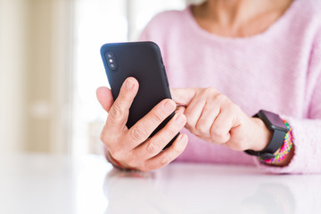 Close up of senior woman using smartphone over white table