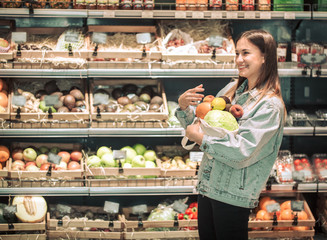 Young girl holding fruits and vegetables in an eco bag on the background of the store