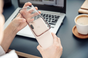 Woman's hands put silicone case on the back side of smartphone.