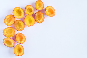 Several fresh ripe plums cut in half on white background