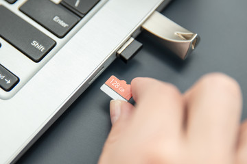 Woman's hand puts in fast, capacoius microSD card to the modern ultrabook.