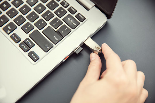 Woman's hand connects design aluminium pendrive to modern ultrabook.