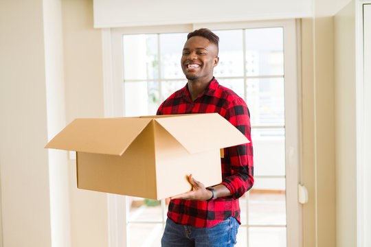 Young african american man holding a carton box, packing cardboard delivery package at home
